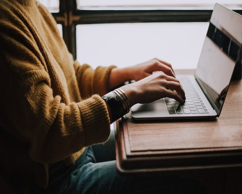 Person working on a laptop beside a bright window